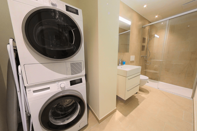 Bathroom with stack washer and dryer, sink, toilet, and shower.