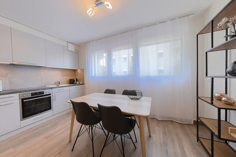 modern kitchen with white cabinets, wooden floor, white dining table, modern chairs, white curtains, oven, sink, faucet, shelves