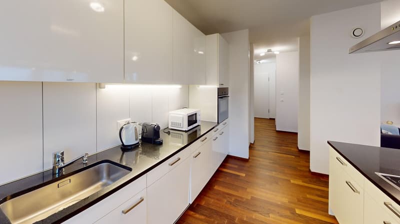 Modern kitchen with white cabinets, stainless steel sink, granite countertop, and hardwood flooring. Appliances include a microwave and a dishwasher.
