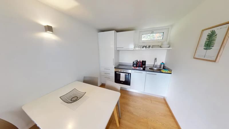 Bright and modern kitchen with white cabinets, stainless steel appliances including a dishwasher, and a dining table with chairs