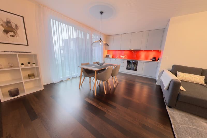 modern dining area with wooden floor, dining table, chairs, white shelves, white curtains, kitchen with white cabinets, orange backsplash, microwave, oven, couch with pillow
