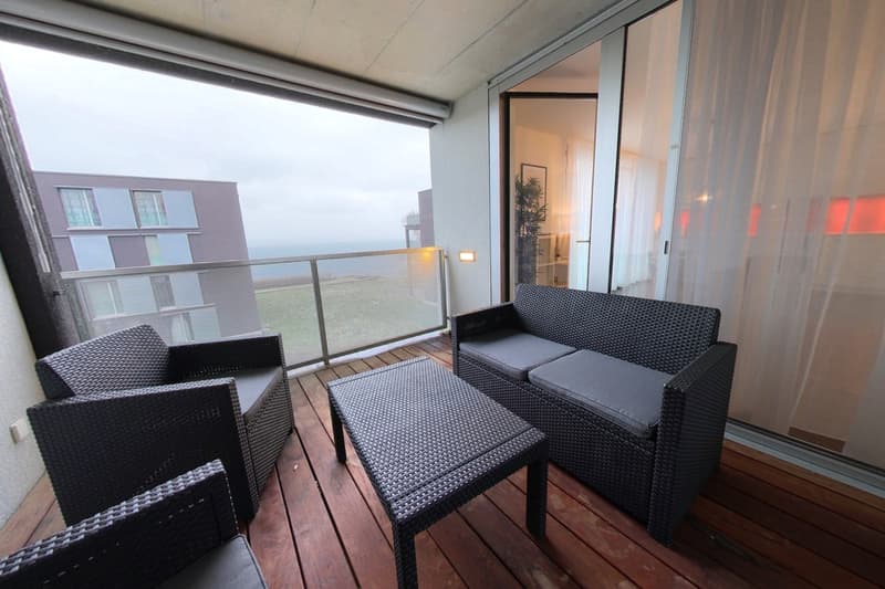 balcony, wicker furniture, wooden floor, large windows, view of the sea