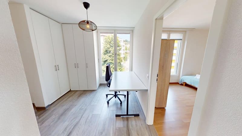 room with desk and chair, large white built-in wardrobes, floor windows