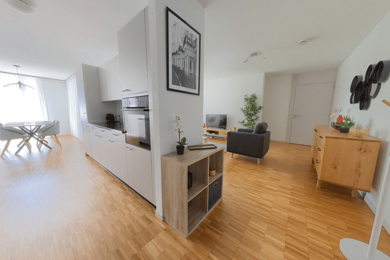 modern kitchen with white cabinets, wooden floor, living room with couch, TV, wooden cabinet, dining table with chairs