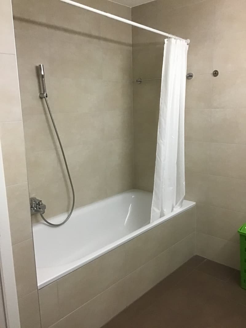 Bathroom with bathtub, shower head, shower curtain, tiled walls, tiled floor