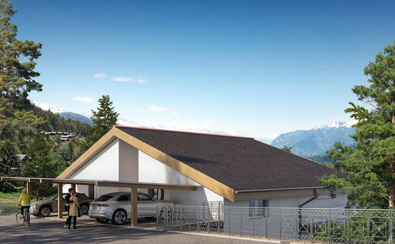 A two-story building with a slanted roof, surrounded by trees and mountains. The building has a covered parking area in the front with space for multiple vehicles.