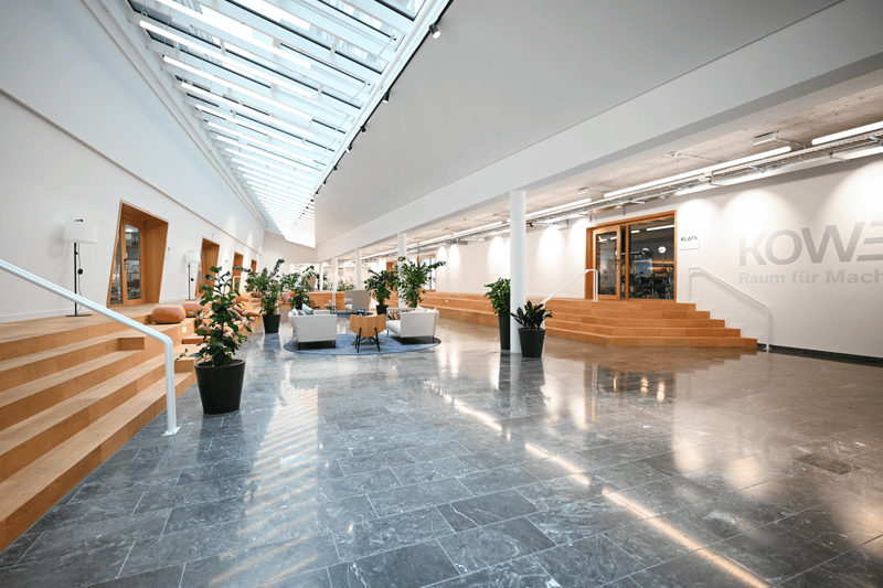 open space, wooden stairs, glass ceiling, multiple potted plants, modern and clean design, office equipment