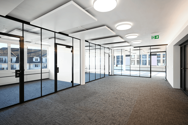 modern office space with glass walls, carpeted floor, large windows, exit sign