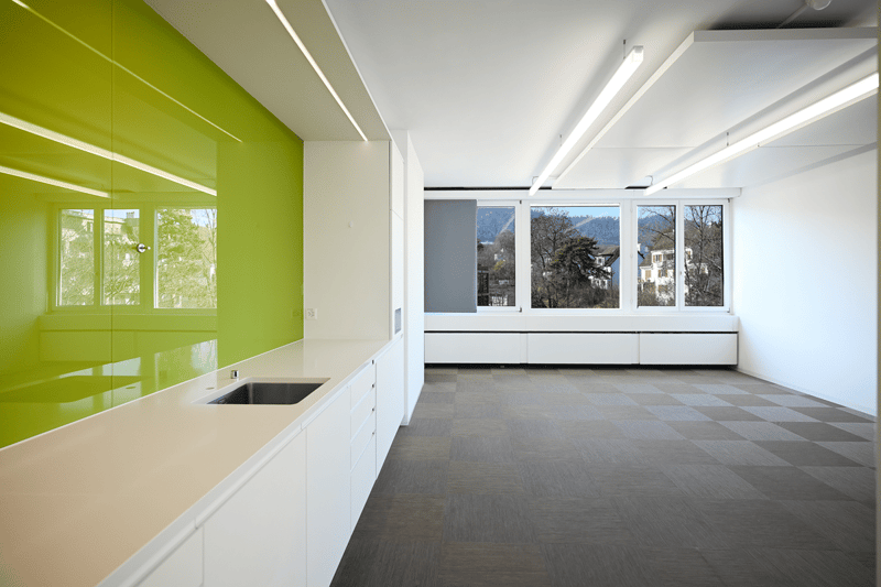 modern kitchen with green wall, white cabinets, sink, windows, tiled floor