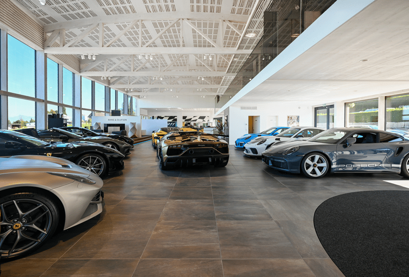 interior view of car dealership with rows of sports cars, glass walls, wooden floor, modern design