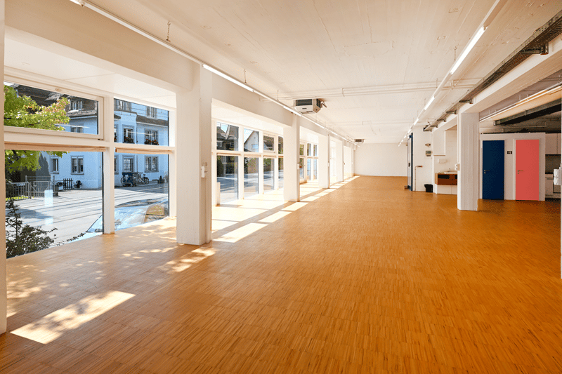 large windows, wooden floor, AC unit mounted on the wall, wide open space