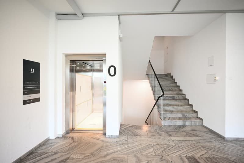 An elevator, a staircase with marble steps, and a marble floor.