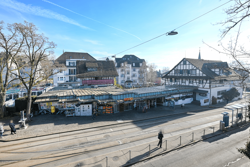 Aerial view of a street with multiple buildings and a tramway station with stores