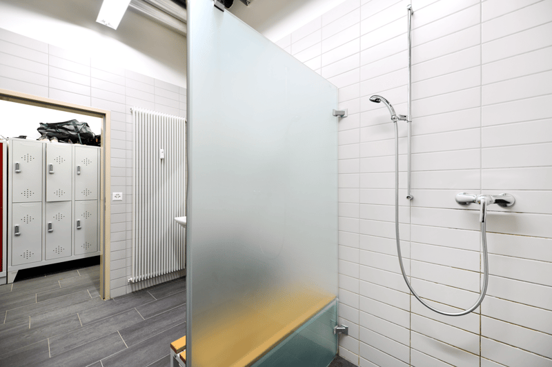shower cubicle with bench, shower, radiator, white tiles, white walls, glass door