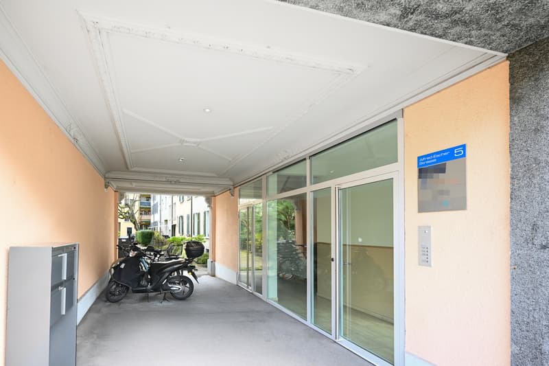 covered entrance with glass doors, scooters parked, mailboxes, entrance to building