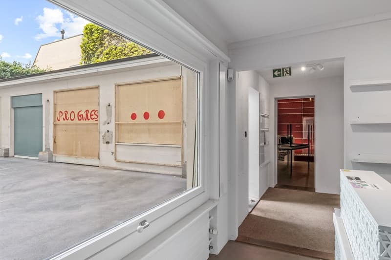 Garage with concrete floor, white walls, radiator, window, door, and exit sign