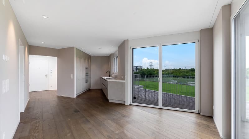 Open plan kitchen and living room with wooden floor, large sliding glass doors, balcony with a fence