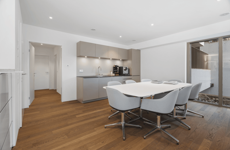 modern kitchen, white countertops, wooden floors, modern light fixtures, table, chairs