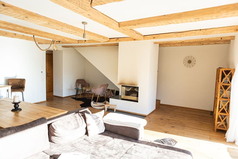 beamed ceiling, wooden floor, white walls, fireplace, large sofa, table with candle