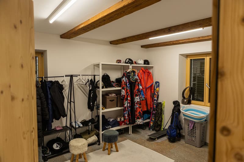 Cloakroom with storage racks, shelves, stools, storage boxes, clothing, and a window.