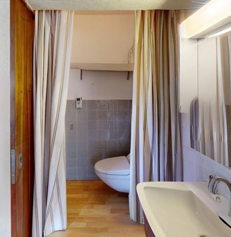 White sink, white toilet, tiled walls, light fixture, faucet, shower curtain
