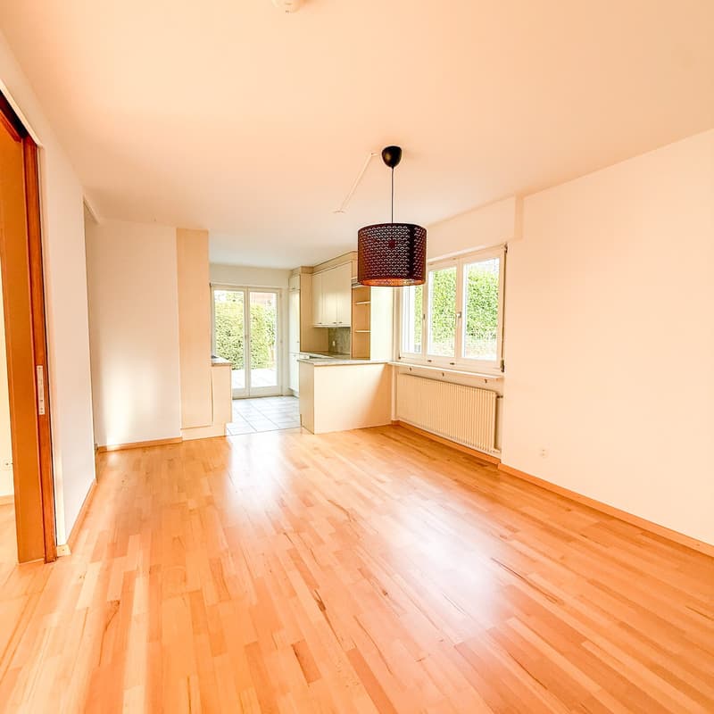 Wooden floor, white walls, two large windows, sliding door, kitchen island, pendant light