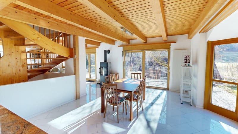 Wooden beams, white tiled floor, a wooden dining table with chairs, a fireplace, wooden staircase