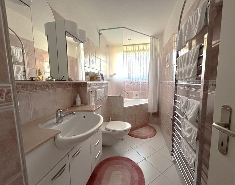 white tile floor, bathtub with shower, modern sink, mirror, toilet, radiator, cabinets, and rugs