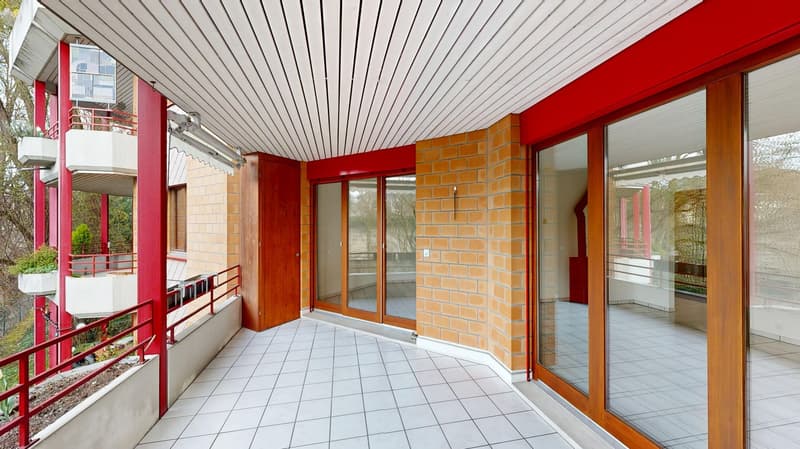 Balcony with white tiles, red railings, glass doors, brick wall, white ceiling