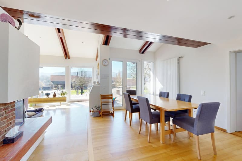 Dining room with wooden table and chairs, fireplace, sliding glass doors, wooden floor, white walls, radiator, clock on wall