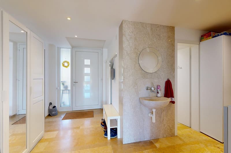 Entrance hall with wooden floor, white walls, white doors, sink, mirror, shoe rack, and a window.