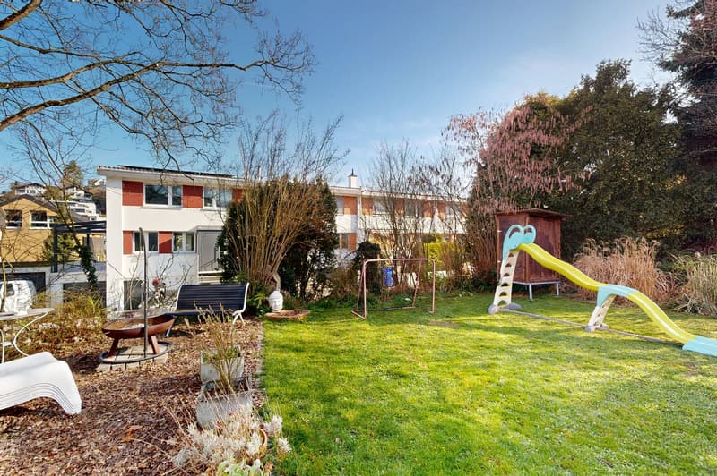 A garden with a slide, bench, and a fire pit.