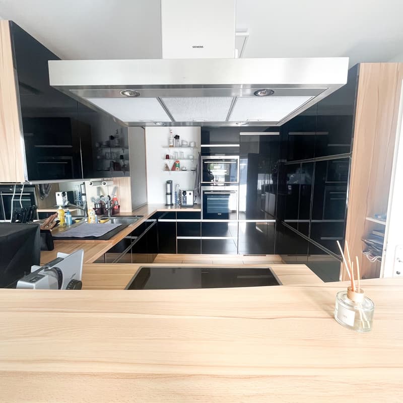 modern kitchen with wooden countertops, black cabinets, stainless steel appliances, large stove, modern kitchen island, under cabinet lighting, open shelving