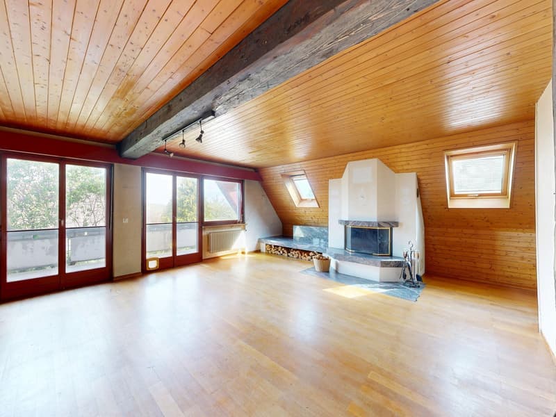 Empty room with wooden floors, wooden walls, and large windows. Features a fireplace, a bench, and a basket. No furniture or equipment present.