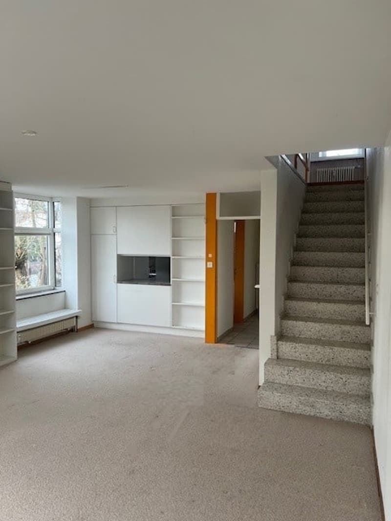 empty room with staircase, windows, built-in cabinets, radiator