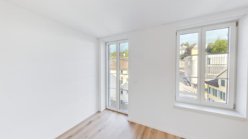 Spacious bedroom with large windows, hardwood flooring, and access to a balcony or terrace.