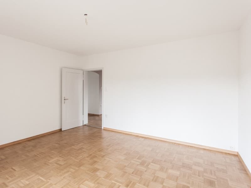 large empty room, white walls, wooden floor, open doors