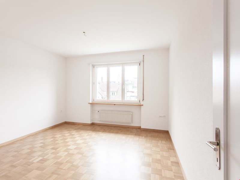 empty room, white walls, wooden floor, large window with a view, white radiator