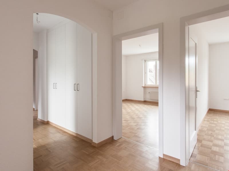 empty room, wooden floor, white walls, arched closet, open door, small window, small balcony