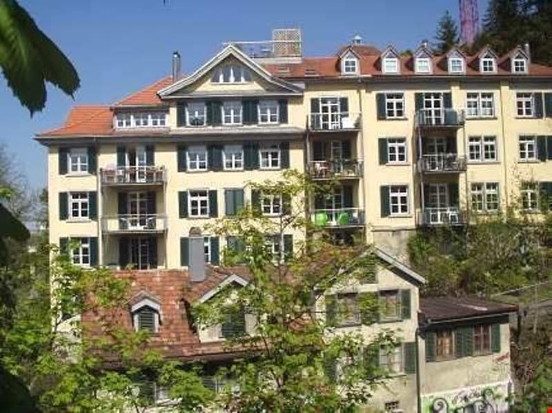 multi-story building, yellow facade, many windows, balconies, red roof