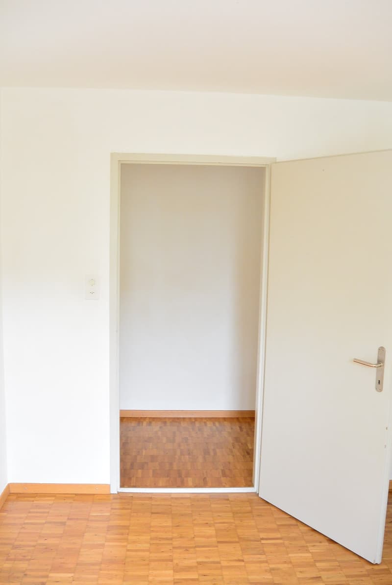 Empty room with a door and wooden flooring, white walls