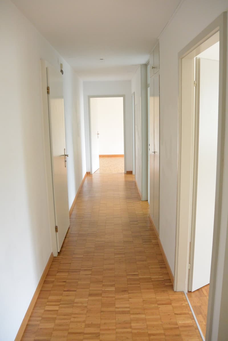 corridor with tile flooring, open doors, white walls, cupboards