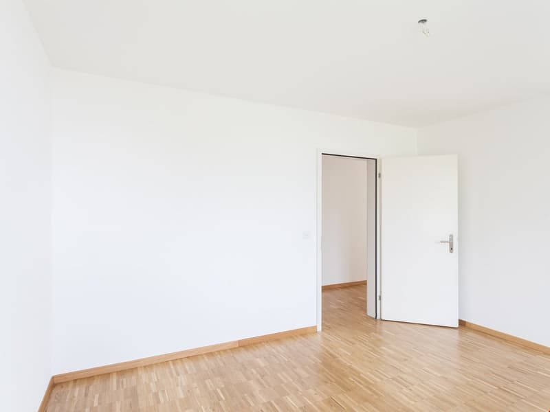 an empty room with wooden flooring and white walls