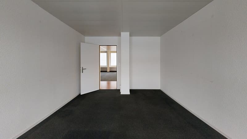 White walls, black carpet, open door, adjacent room visible