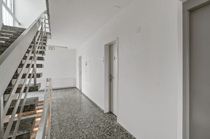 white walls, grey marble flooring, stairs with metallic railing, door on right side