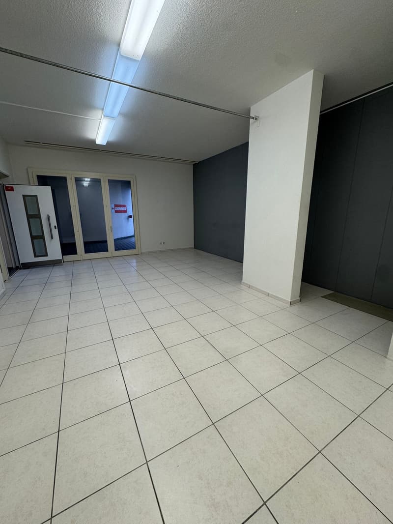 Empty room with white tiles, white walls, glass doors, and a white pillar