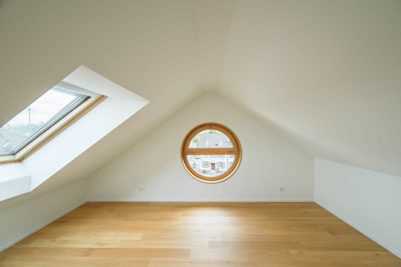 Dachzimmer mit grossem Dachfenster sie einem runden Fenster als Eyecatcher