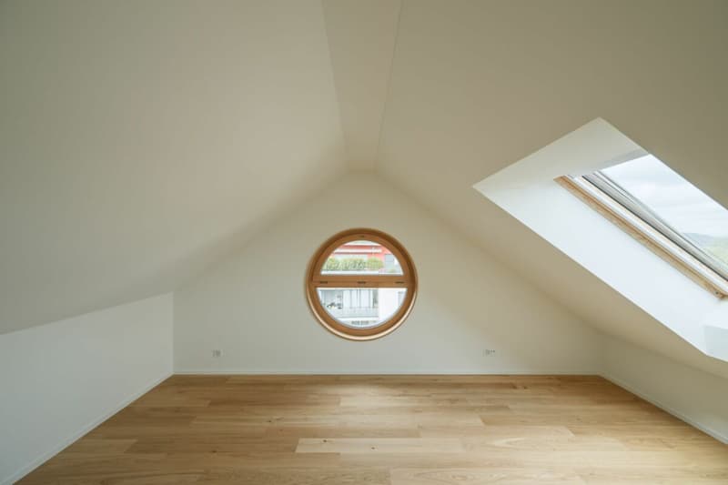 Das Dachzimmer mit grossem Dachfenster und zusätzlichem Rundfenster