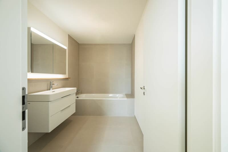 Badezimmer mit Badewanne, WC, grossem Lavabo, und Doppelspiegel