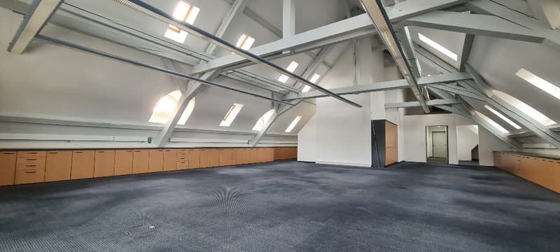 Empty room with high ceilings, wooden cabinets, and windows